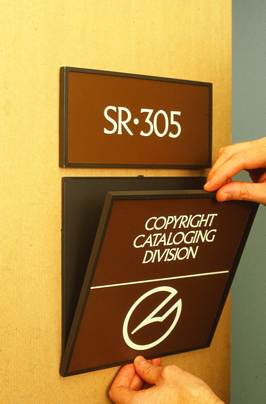 Hands installing signs on a wall