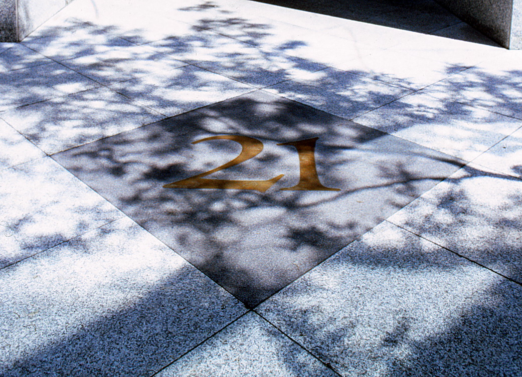 Closeup of the sidewalk featuring the 21 set into it surrounded by a design.
