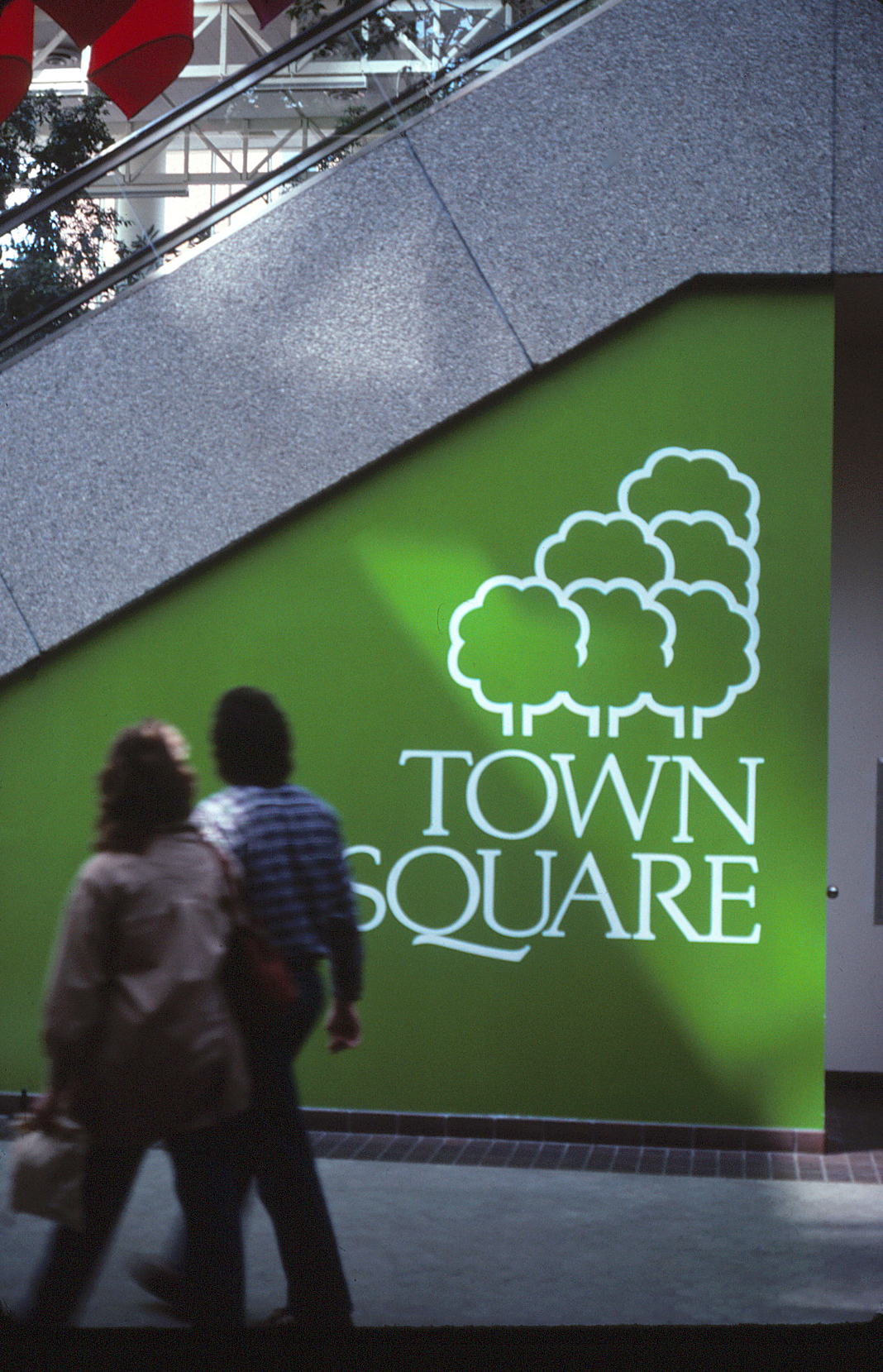 The Saint Paint Town Square logo on a wall beneath an escalator.