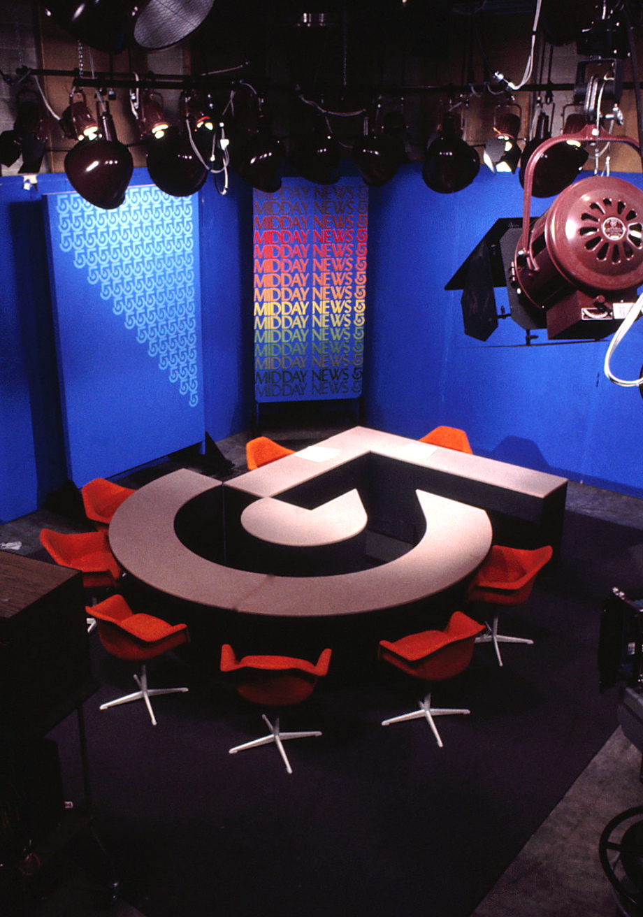 News TV set with table and chairs featuring symbol